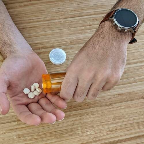 Pills spilling from a bottle into a hand.